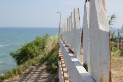 Close-up of picket fence by sea against clear sky