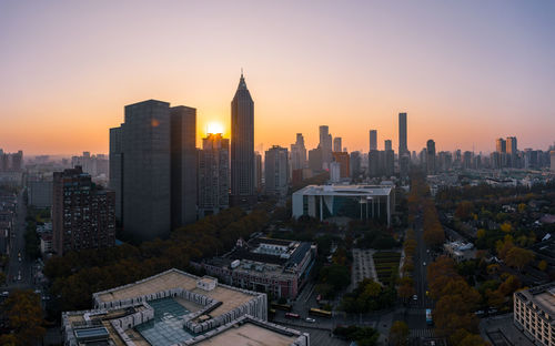 Modern buildings in city against sky during sunset