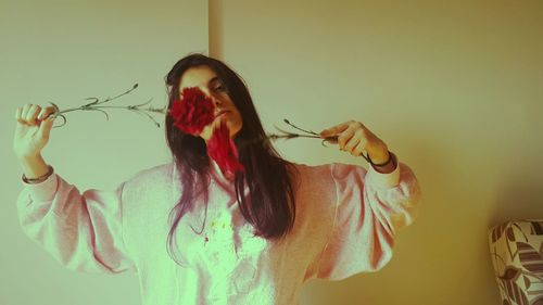 Portrait of young woman standing against wall at home