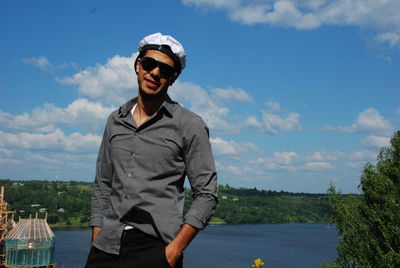 Young man wearing sunglasses standing against volga river