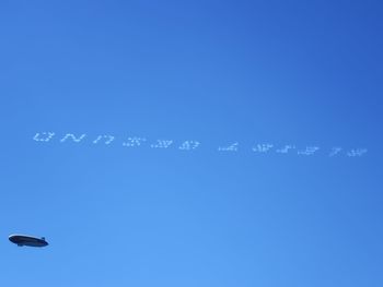 Low angle view of birds flying against blue sky