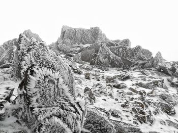 Snow covered rocks against clear sky