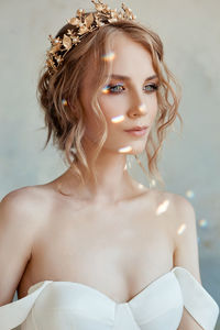 Close-up of beautiful bride wearing dress standing against wall