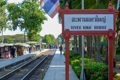 Information sign by railroad tracks against trees