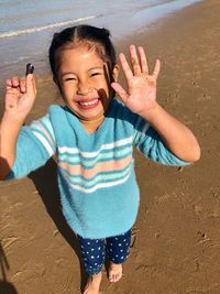 Portrait of smiling girl holding seashell while standing at beach