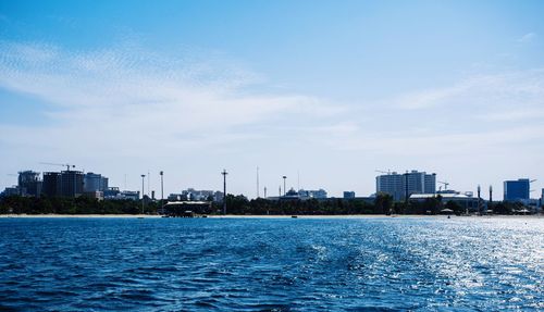 Sea by buildings against blue sky