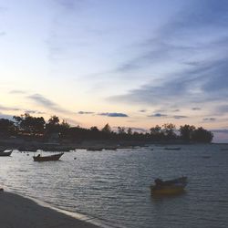 View of boats in river against cloudy sky