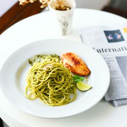 High angle view of spaghetti garnished with mint leaf and fried chicken on table