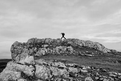 Low angle view of man standing on rock against sky