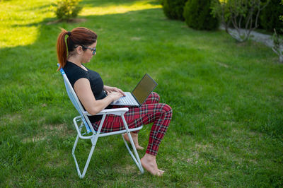 Side view of man using mobile phone in grass