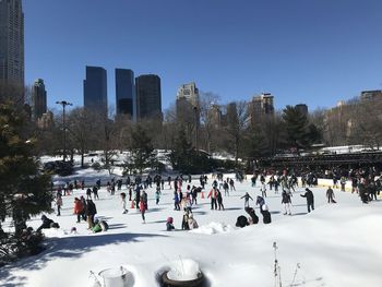 People on snow covered city against sky