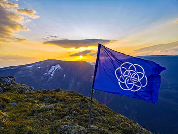 Scenic view of earthflag on mountain against sky during sunset