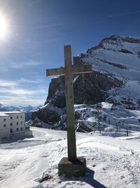 Cross on snow covered field against sky