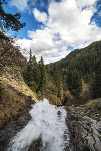 Scenic view of river flowing amidst mountains against sky