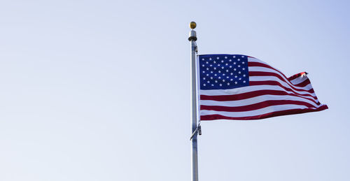 Low angle view of flag against clear blue sky