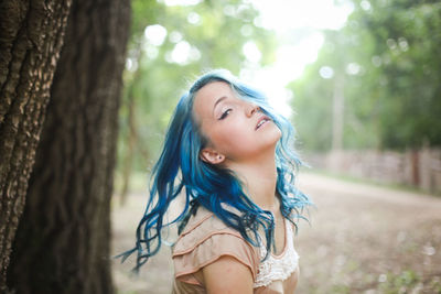 Beautiful young woman with tree trunk in forest