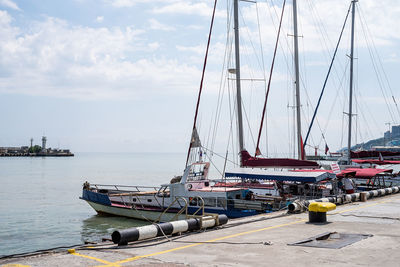 Sailboats moored in sea against sky