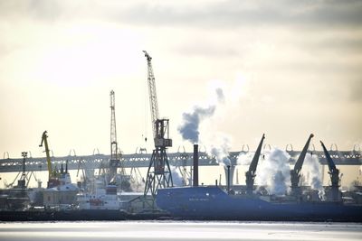 Cranes at commercial dock against sky