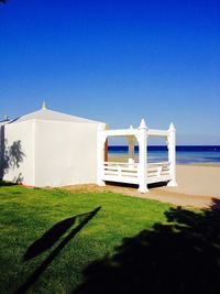 Built structure by sea against clear blue sky