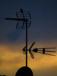 Low angle view of weather vane against sky during sunset