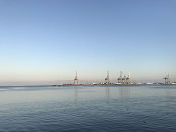 Cranes at commercial dock against clear blue sky