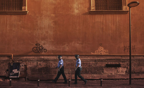 Rear view of people walking on wall