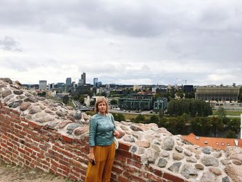 Woman standing by retaining wall at gediminas tower against sky