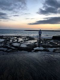 Silhouette man standing on beach against sky during sunset