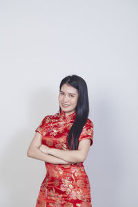 Portrait of smiling young woman standing against white background