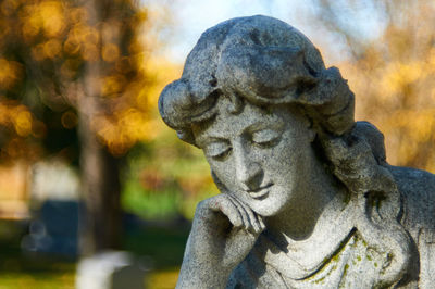 Close-up of female statue at cemetery during autumn