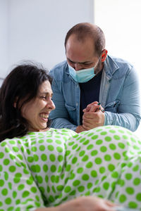 Man wearing mask consoling pregnant woman at hospital