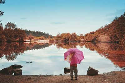 Woman standing by lake against clear sky