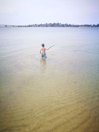 Full length of shirtless boy in sea against sky