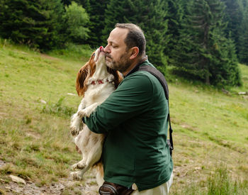 Moment when adorable cavalier king charles spaniel is kissing a man, her best friend