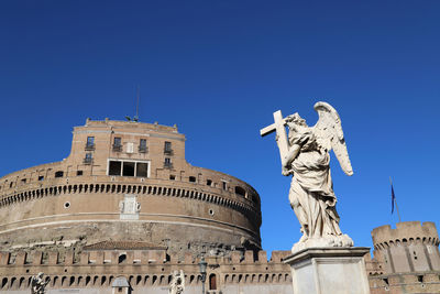 Low angle view of statue of building against blue sky