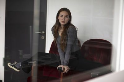 Portrait of young woman standing against wall