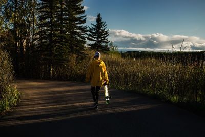 Rear view of man standing on road against sky