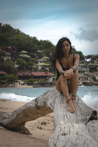 Portrait of beautiful young woman sitting on beach
