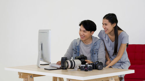 Young couple looking at camera while sitting on table