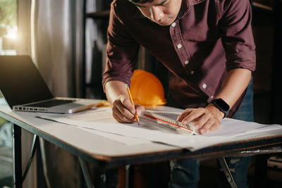 Midsection of man using laptop at table