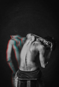 Rear view of shirtless man against black background