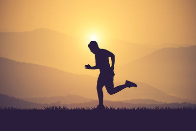 Silhouette man on field against sky during sunset