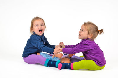 Happy siblings playing in snow against white background