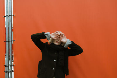 Mid adult man standing against orange wall