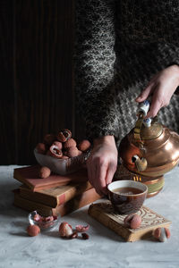 A woman pours tea from a copper teapot into a cup,still life with lychee,cozy