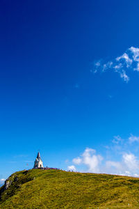 Low angle view of church on mountain against blue sky