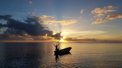 Silhouette person in sea against sky during sunset