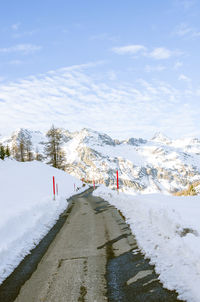 Road leading towards snow covered mountain against sky