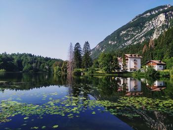 Scenic view of lake by trees and houses against sky