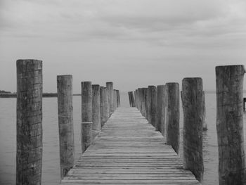 Wooden pier at beach against sky